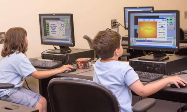 Summer campers on seated in front of a computer creating video games